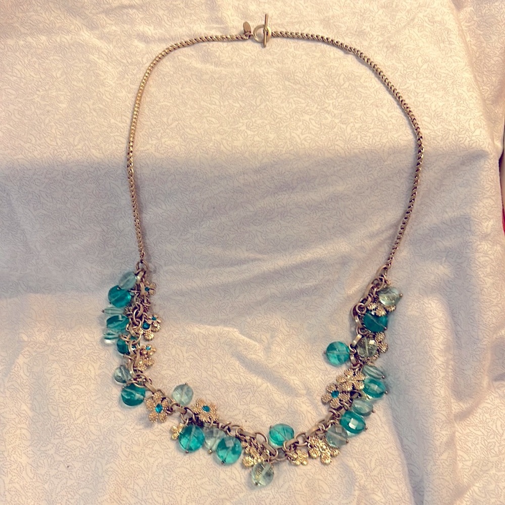 Gold necklace with flower charms and light blue/teal blue hanging stones